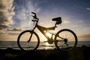 a bicycle is parked on a rock near the ocean photo