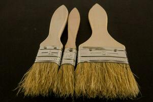 three brushes with wooden handles and bristles photo