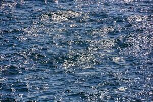 the surface of the ocean is blue and has small bubbles photo