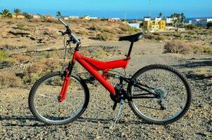 un rojo montaña bicicleta es estacionado en el suciedad la carretera foto