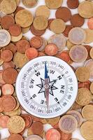 a compass is surrounded by coins on a white background photo