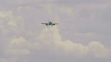 Passenger plane approaching for landing. Aircraft flies, front view. Airliner with unrecognizable green livery descending. Flight arrival video