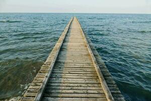 a wooden pier stretches out into the ocean photo