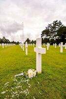 a white cross and flowers on the grass photo