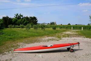 a red and white kayak on a gravel road photo