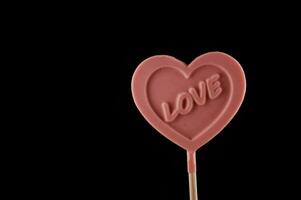 a pink heart shaped lollipop with the word love written on it photo