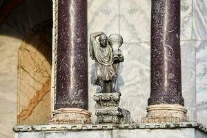 a statue of a man holding a water jug on a building photo