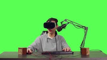 Streamer broadcasting live online games from his desktop while participating online using virtual reality equipment. Asian person streaming videogames, content creator on greenscreen. video