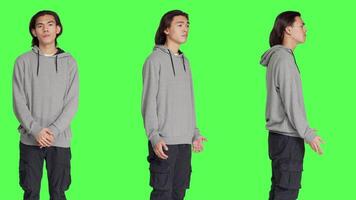 Young guy doing no gesture in studio, expressing negativity and disapproval over isolated greenscreen background. Asian man being displeased and disagreeing with something. video