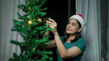 mujer decora linda regalos felizmente en el Navidad árbol a hogar video