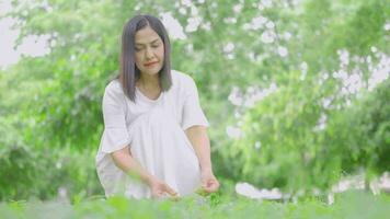 entspannt Frau Sitzung bewundern das Garten halten Blumen video