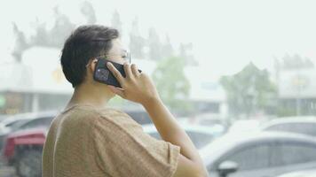 A man walks and talks on the phone while rain is falling in the area. video