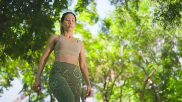 Aziatisch vrouw is beoefenen yoga in de park Aan de groen gras. video