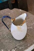 a white and blue jug sitting on a concrete slab photo