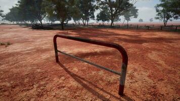 A rustic red dirt field with a charming fence and trees in the background video