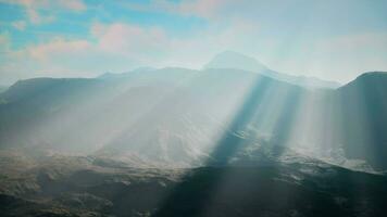 panoramico Visualizza di luce del sole rottura attraverso il nuvole al di sopra di maestoso montagne video