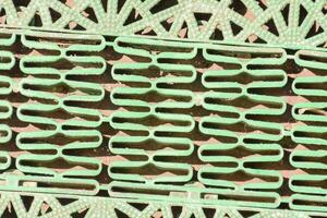 a green metal grate with a pattern of geometric shapes photo