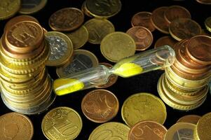 an hourglass sitting on top of a pile of coins photo