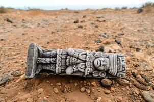 a stone statue laying on the ground in the desert photo