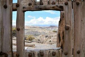 a window in an old wooden fence with a view of the desert photo