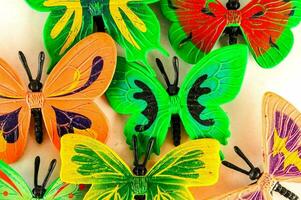 a group of colorful plastic butterflies on a white surface photo