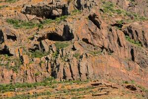 a mountain with a large rock face and vegetation photo