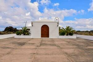 a white church with a wooden door and palm trees photo