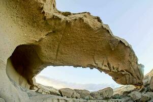 a large rock formation in the desert with a large arch photo