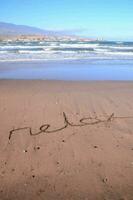 the word relax written in the sand on the beach photo