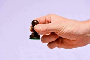 a hand holding a small wooden chess piece photo