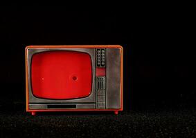 un antiguo televisión con un rojo pantalla en un negro antecedentes foto