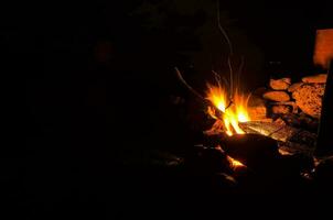 a campfire is lit up at night with a dark sky photo