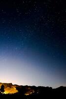 the night sky over a mountain range with stars photo