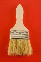 a brush with a wooden handle on a red background photo