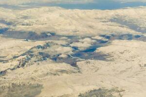 an aerial view of snow covered mountains from an airplane photo