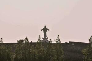 a statue of jesus is silhouetted against the sky photo