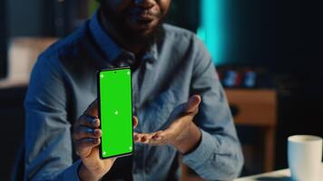 Content creator films chroma key smartphone video review for tech enthusiasts, close up. Viral online star hosts technology internet show, unboxing isolated screen cellphone, focus on product