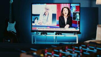 Close up shot of TV left open at night in cozy dimly lit apartment showing broadcast of news story. Home entertainment system showing television reports in living room, panning shot video