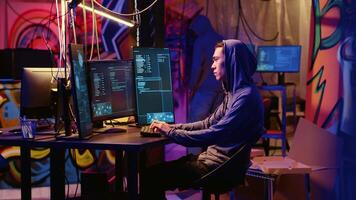 Evil hackers doing data breaches and financial theft in graffiti painted hideout. Rogue programmers stealing users bank account credentials, targeting low security passwords video