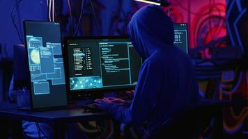 Hackers in dark room running code to breach defenses and exploit weaknesses in computer systems. Evil developers in basement getting past companies security networks, handheld camera shot video