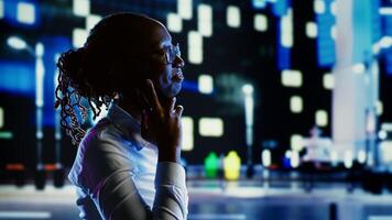 African american woman talking over the phone with husband using cellphone to feel more safe strolling around dimly illuminated empty avenues at night, blurry urban background with bokeh lights photo