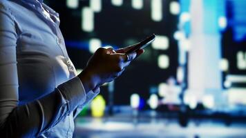 Woman using smartphone to order cab, feeling unsafe walking around empty streets at night. Girl waiting for taxi to pick her up while wandering in dimly illuminated urban environment, close up photo