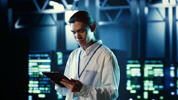 Proactive employee walking through data center electronics providing processing resources for different workloads. Organized engineer evaluating server rigs tasked with solving complex operations photo