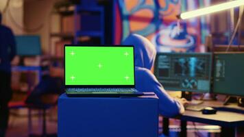 Green screen laptop in bunker with graffiti walls left behind by hackers to act as decoy. Mockup device running script pinging wrong location to cybercriminal law enforcement chasing them video