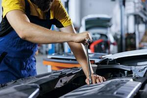 Mechanic in car service using professional mechanical tool to repair broken alternator. Proficient worker in garage fixing client automobile, ensuring optimal automotive performance, close up photo