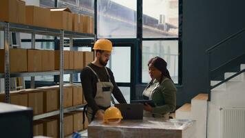 Dolly out shot of employees fulfilling warehouse inventory checkup, keeping quality standards high. Experts in storage room checking labels on cached retail stock, crosschecking delivery info photo