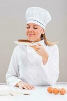 Beautiful female chef has made delicious cake and she is smelling it. photo