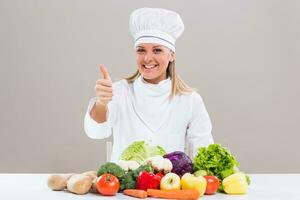 Beautiful chef showing bunch of vegetable and thumb up. photo