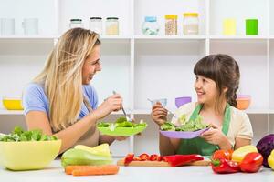 contento madre y su hija disfrutar haciendo y teniendo sano comida juntos a su hogar. foto