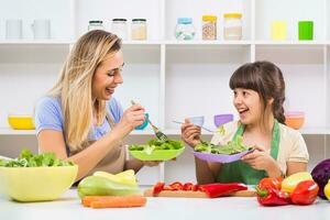 Happy mother and her daughter enjoy making and having healthy meal together at their home. photo